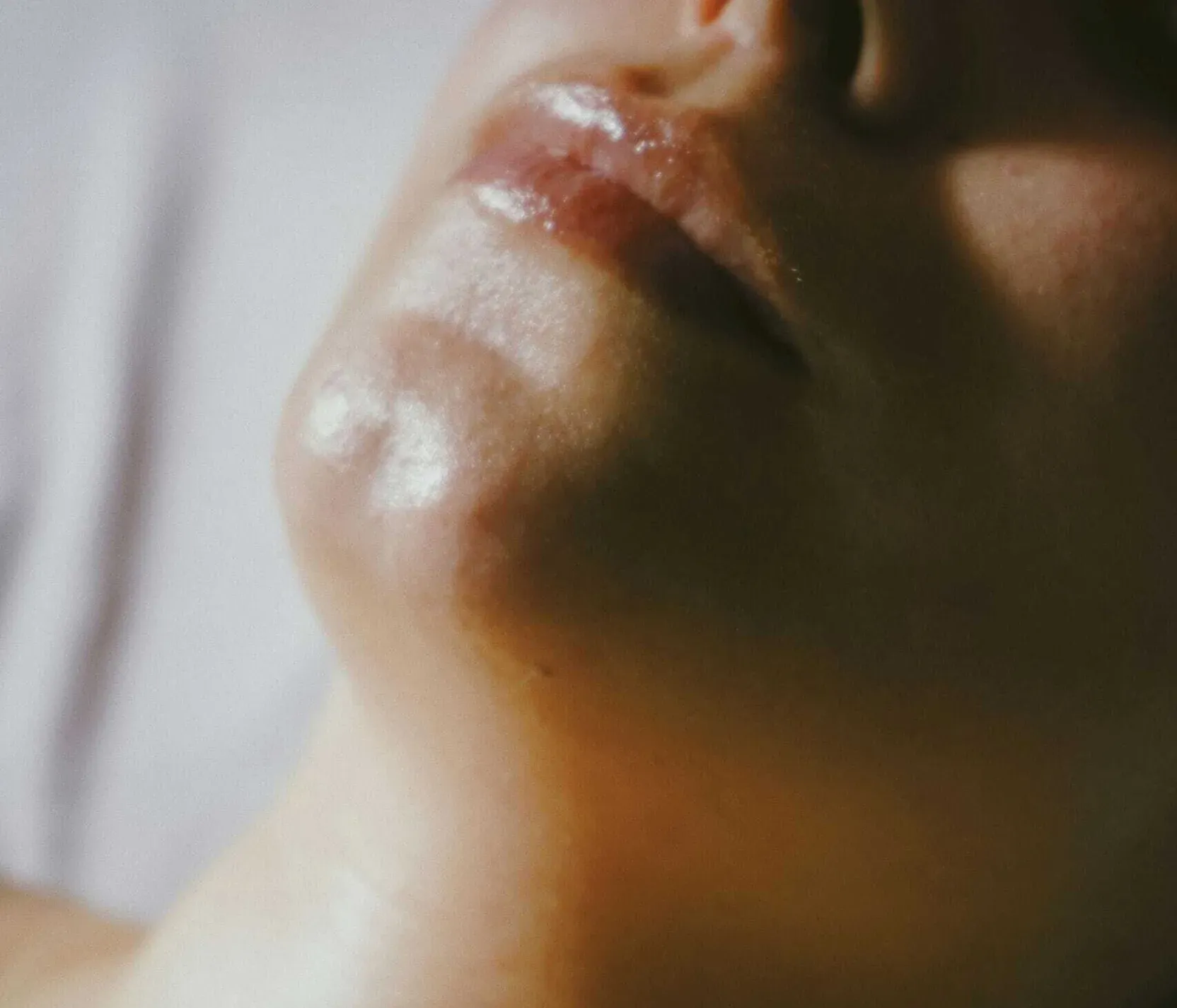 Nahaufnahme eines friedlichen Gesichts einer Person, die Augen geschlossen, die Finger berühren sanft die Stirn. Die Haut wirkt taufrisch und vermittelt ein Gefühl von Ruhe und Entspannung.