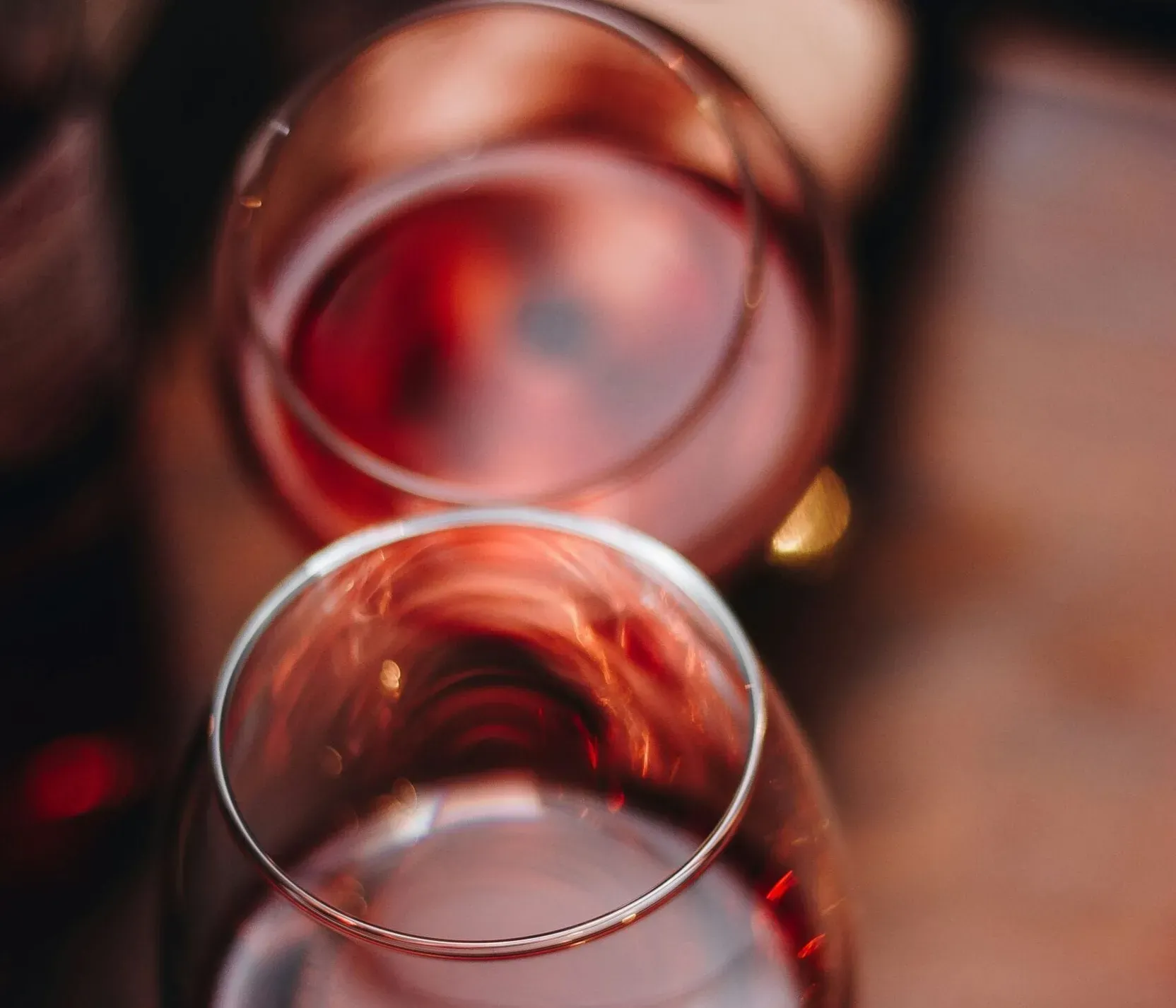 Drei Weingläser mit roséfarbenem Wein, Blick von oben, auf einem Holztisch, mit unscharfem Hintergrund.